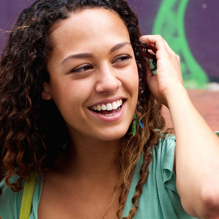 happy-young-woman-sitting-on-steps-with-a-mobile-PR4TN3M